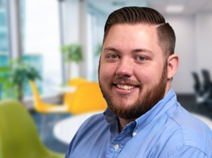 Mike - portrait of man smiling with beard and blue button up