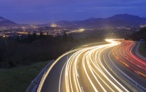 Winding road at night with headlights trailing