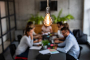 Meeting happening behind with lightbulb in foreground